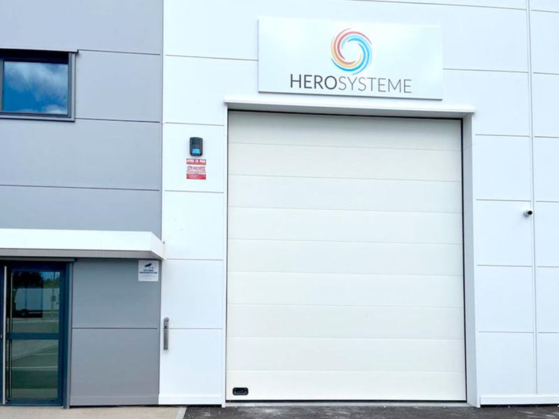 La façade de HEROSYSTEME à Aulnay-sous-Bois : enseigne, porte sectionnelle et entrée vitrée